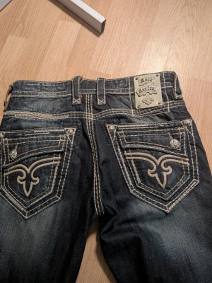 Mörkblåa jeans från Rock Revival - Säljer ett par mörkblåa Rock Revival jeans som är riktigt feta. Säljer pågrund jag ska ut och resa. Vid frågor bara skicka DM