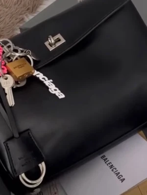 Svart  handväska  - Väskan är i utmärkt skick. Kartongen finns inte kvar, den slängdes vid flytten. Dammpåse och nyckelring finns. Äkta mjukt läder.Skriv, så tar jag fler bilder.