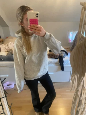 Grå hoodie med tryck  - Säljer en ljusgrå hoodie från gina tricot med tryck på bröstet och ryggen. Hoodien har en klassisk passform, huva och långa ärmar. Perfekt för en chill och avslappnad stil. Materialet känns mjukt och skönt. 