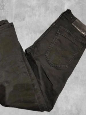 Svarta jeans - Säljer ett par svarta jeans med klassisk femficksdesign och svarta sömmar. Jeansen har en stilren look och passar perfekt till en avslappnad eller trendig outfit. Materialet känns mjukt och stretchigt för extra komfort.