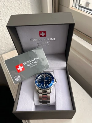 swiss alpine military klocka - En rikigt stil ren klocka nu till sommaren passar till allt! Köpte den för 4499kr väldigt bra skick bara några enstaka repor! Tveka inte på att höra av er vid frågor eller funderingar