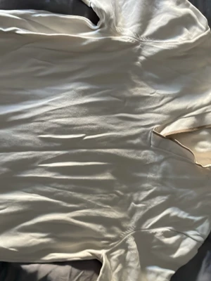 Vit sidenliknande skjorta från Riley - Säljer en stilren vit skjorta från Riley med klassisk krage och slät yta som ger ett lyxigt intryck. Skjortan har en enkel design utan synliga knappar och är tillverkad i ett material som liknar siden. Perfekt för dig som gillar minimalistisk och clean stil.