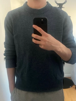 Blå stickad tröja  - En enkel och stilren blå stickad tröja med rund halsringning och ribbade muddar vid ärmslut och nederkant. Storlek M. Vid fråger eller funderingar är det bara höra av sig.