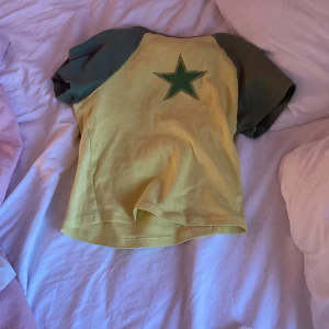 Gul och grön t-shirt med stjärna - Cool t-shirt från FB sister i gul med gröna ärmar och en stor grön stjärna på ryggen. Kortärmad modell i mjuk bomull, perfekt för en avslappnad och trendig look.