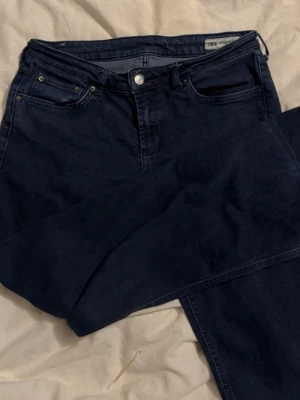 Mörkblå bootcut jeans från Zara - Säljer ett par mörkblå jeans från Zara med bootcut passform och klassisk femficksdesign. Jeansen har låg midja och stängs med knapp och dragkedja. Tillverkade i ett mjukt denimtyg som är bekvämt att bära. Perfekta för en avslappnad och stilren look.