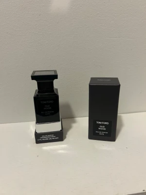 Tom Ford Oud Wood Eau de Parfum 50ml - Tom Ford Oud Wood Eau de Parfum i en elegant svart fyrkantig glasflaska med matchande svart lock. Parfymen har en lyxig och stilren design och levereras i originalförpackning. Perfekt för dig som gillar exklusiva dofter med träiga och orientaliska toner.