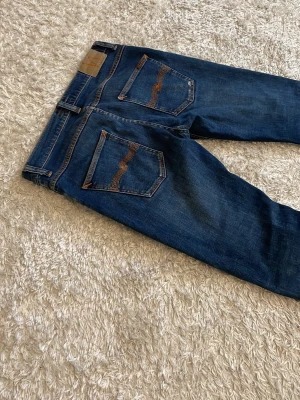 Nudie jeans indigo myth - Riktigt sköna nudie jeans med en snygg wash. Storlek är 31/30. De är i mycket bra skick men är lite trasiga vid gylfen men det går lätt att fixa. Skriv vid minsta fundering.