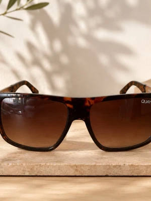 Bruna solglasögon från Quay Australia - Snygga solglasögon från Quay Australia med brunmelerad båge och rektangulär form. Glasen är tonade i brunt och bågarna har en klassisk, trendig look. Perfekta för soliga dagar och ger en cool vibe till din outfit.