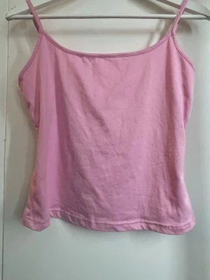 Rosa linnetopp med smala axelband - Söt rosa linnetopp med smala axelband och enkel design. Perfekt för varma dagar och lätt att matcha med jeans eller kjol. Tillverkad i mjuk bomull som känns skön mot huden. (Finns också i blå)