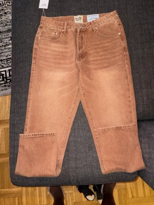 Bruna raka jeans från Gallery Dept. - Säljer ett par bruna jeans från Gallery Dept. med rak passform och klassisk femficksdesign. Jeansen har en unik tvättad look och synliga sömmar vid benen för en cool detalj. Tillverkade i kraftig denim som ger en schysst vintagekänsla.
