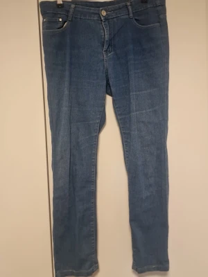 Blå slim fit jeans med fem fickor - Snygga blå slim fit jeans med klassisk femficksdesign och normal midja. Jeansen har dragkedja och knapp framtill samt bälteshällor. Materialet är denim med lätt stretch för extra komfort. Perfekta för en avslappnad och trendig look.
