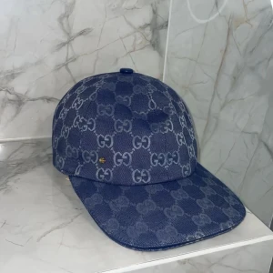 Mönstrad keps - Säljer en blå keps med det klassiska mönstret över hela kepsen. Kepsen har böjd skärm och är tillverkad i ett denimliknande material. Perfekt för dig som vill ha en stilren accessoar med lyxig känsla.