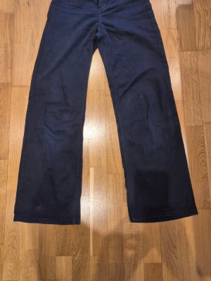 Mörkblå jeans från H&M - DIVIDED - Mörkblå byxor med utsvängda ben och hög midja. Tillverkade i ett mjukt denimliknande material som ger en bekväm känsla.