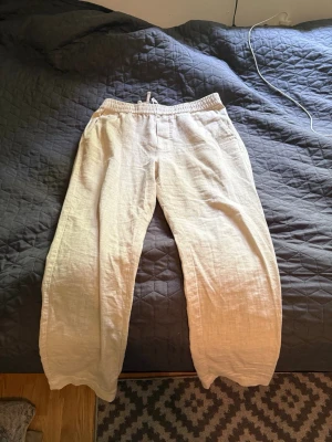 Ciszere linnebyxor  - Snygga och luftiga beiga linnebyxor med avslappnad passform och resår i midjan. Byxorna har raka ben och sidofickor, perfekta för en chill och stilren look. Materialet är 100% linne vilket gör dem extra svala och bekväma. Inge täcken på användning