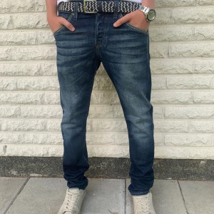 Mörkblå jeans från Jack & Jones Storlek 30/30 - Snygga mörkblå jeans från Jack & Jones med klassisk femficksdesign och coola slitningar framtill. Jeansen är av modellen Slim Fit/Glen. Jeansen är i mycket gott skick. Priset är inte hugget i sten!
