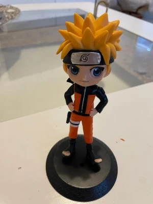Naruto Uzumaki cosplay figur - Cool cosplayfigur av Naruto Uzumaki från anime-serien Naruto. Figuren har orange och svart dräkt, svart pannband och spretigt gult hår. Perfekt som accessoar till cosplay eller maskerad. Tillverkad i plast och står på en rund svart bas.