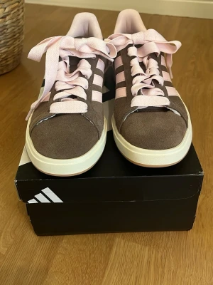 Bruna Adidas sneakers med rosa detaljer - Nya adidas sneakers. Aldrig använda. Jättefina men tyvärr för små. Storlek 38 2/3. Nypris: 1100 man ser den rätta färgen på bild 3