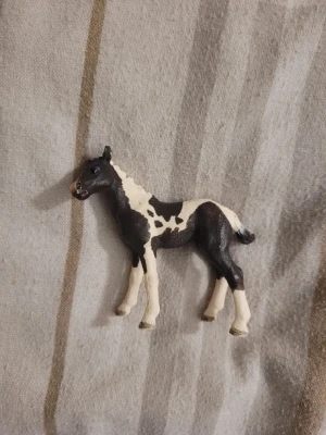 Svartvit hästfigur  - Säljer en liten hästfigur med svart och vit färg. Figurerad i stående position med detaljerad målning och realistisk form. Perfekt som prydnad eller leksak för samlare och hästälskare.