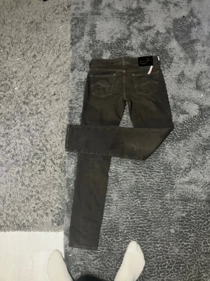 Svarta jeans från Jacob Cohen - Säljer ett par svarta jeans från Jacob Cohen med klassisk femficksdesign och italiensk flaggdetalj vid bakfickan. Jeansen har smal passform och är tillverkade i ett stretchigt material för extra komfort.