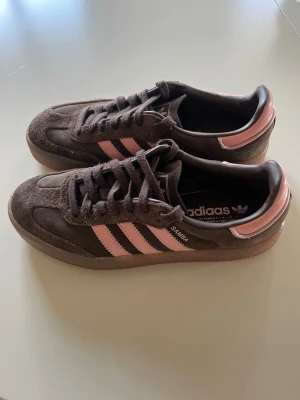 Adidas Samba brun/rosa sneakers - Säljer mina supersnygga vårskor som tyvärr inte kommit till användning mer än 2 gånger. Slutsålda på hemsidor!!  Adidas Samba sneakers i brunt mocka och läder med klassiska rosa stripes och detaljer. Skorna har gummisula och låg profil, perfekt för en avslappnad och trendig stil. Ikonisk modell med snygg färgkombination och retrovibbar.