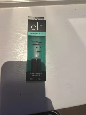 e.l.f. Power Grip Primer 24ml - e.l.f. Power Grip Primer är en genomskinlig primer i en smidig tub på 24 ml. Förpackningen är turkos med svart och vit text. Primern ger en slät bas för smink och hjälper makeupen att sitta längre. Perfekt för dig som vill ha en fräsch och hållbar look.