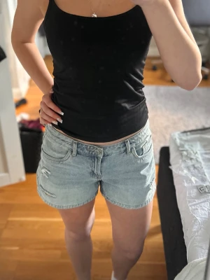 Ljusblå denimshorts med slitningar - Snygga ljusblå denimshorts  med slitna detaljer och klassisk femficksmodell. Perfekta för sommaren med en avslappnad passform och bälteshällor. Styla med ditt favoritlinne för en chill look. Säljer då de ej kommer till användning längre 💕