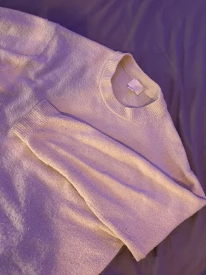 Vit stickad tröja från H&M - Mysig vit stickad tröja från H&M med rund halsringning och långa ärmar. Tröjan har ribbade muddar vid hals, ärmslut och nederkant. Perfekt för lager på lager och enkel att matcha med olika outfits.