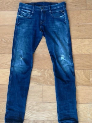 Blå straight fit jeans från Replay - Snygga blå straight fit jeans från Replay med slitningar på knäna och klassiska fem fickor. Modell: Ambas hyperflex Storlek: W29 L32