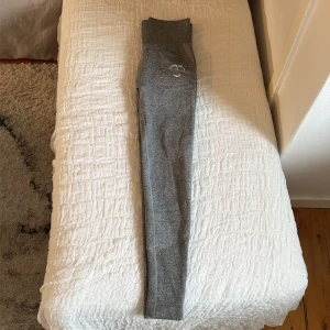 Grå träningstights med scrunch från Peach - Säljer ett par grå träningstights med hög midja. Materialet är stretchigt och mjukt, perfekt för träning eller chill. Tight passform som framhäver benen. Endast använda en gång.