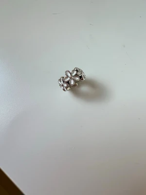Silvrig blomberlock från Pandora - Snygg berlock som knappt är använd, ordinarie pris är 349kr, jag säljer den för 250kr