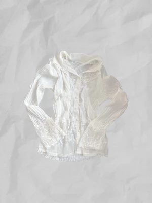 Vintage blus med spetsdetaljer - Säljer en krämvit blus med långärmad design, genomskinligt material och dekorativa knappar! 🤍Jag köpte den i Depart.A.Mental, men använder den inte längre.
