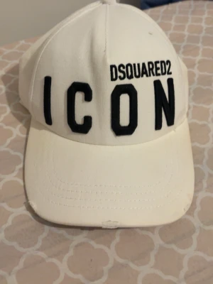 Dsquared 2 keps - Säljer en stilren keps från Dsquared2 med den klassiska “ICON”-texten framtill i svart. Trendig modell som passar till det mesta och ger en clean look.  ✔ Justerbar storlek baktill ✔ Bekväm passform ✔ Tydlig logga ✔ Fint skick (mindre tecken på användning finns, se bild)  Perfekt till både vardag och sommaroutfits ☀️