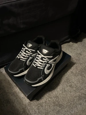 B30 skor vit svarta  - Snygga svarta b30 sneakers med vita och grå detaljer samt vita skosnören. Skorna har en sportig design med mesh och läderpaneler, samt en tjock vit sula. Perfekta för dig som vill ha en exklusiv och trendig look.