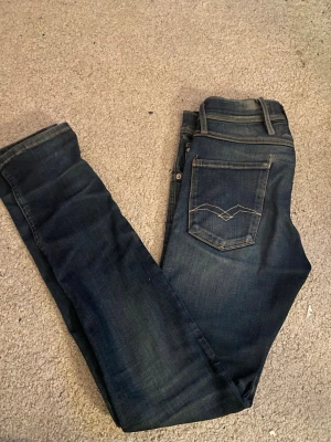Mörkblå slim jeans från Replay - Snygga mörkblå slim jeans från Replay i modellen anbass. Jeansen har normal midja och är tillverkade i mjuk bomull med lite stretch för extra komfort. Riktigt snygga och har en mörkare blå med lite ljusa detaljer. Skriv vid minsta fundering🫵🏻
