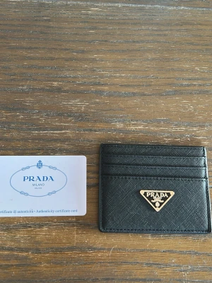 Svart kortfodral - Snyggt svart kortfodral  i saffianoläder med guldfärgad metallogo framtill. Fodralet har flera kortfack och en stilren, minimalistisk design som passar perfekt i fickan. Autenticitetskort medföljer.