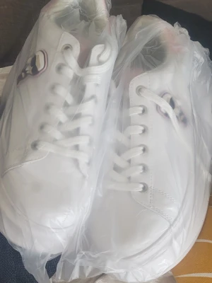 Helt nya Karl Lagerfeld plattformsneakers vita storlek 37 – aldrig använda! -  Säljer ett par helt oanvända Karl Lagerfeld sneakers i storlek 37! Vita skinnsneakers med tjock plattformsula, fin rosa detalj på hälen och den klassiska IKONIK Karl-figuren som patch på sidan. "KARL" står på tungan och "KARL LAGERFELD" på sulan. Skorna är i absolut nyskick – aldrig använda,              Tyvärr ingen originalkartong medföljer (den gick tyvärr förlorad). Supersnygga!