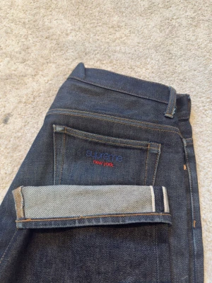 Supreme raw denim selvedge jeans blå - Säljer ett par mörkblå raw denim selvedge jeans från Supreme med broderad logga på bakfickan. Klassisk rak passform, kontrastsömmar. Perfekta för dig som gillar streetwear och vill ha en clean look.  Stlr 30 men passar mig som vanligtvis har 32/32 galant. Köpta på ettresex i Stockholm för 1800, kvitto finns. 
