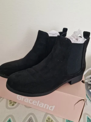 Svarta chelsea boots från Dinsko - Säljer ett par svarta chelsea boots från Dinsko (XIT). De har klassisk resår på sidorna, låg klack och är gjorda i mockaimitation. Perfekta för dig som vill ha en stilren och enkel look till hösten eller vintern. Storlek 39. Perfekt skick, amvända en gång. 