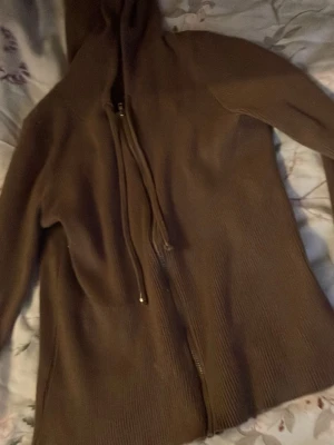 Brun hoodie med dragkedja - Mysig brun hoodie med dragkedja framtill och huva. Tillverkad i ett stickat material som ger en avslappnad och chill vibe. Perfekt för lager på lager och passar till det mesta i garderoben. Inga synliga loggor eller tryck.