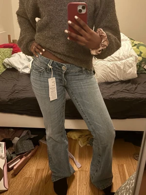 Blå lowwaist bootcut jeans - Säljer ett par klassiska blå bootcut jeans med låg midja och snygg tvätt. Jeansen har fem fickor, bälteshällor och stängs med knapp och dragkedja. Perfekta till en avslappnad och trendig look.