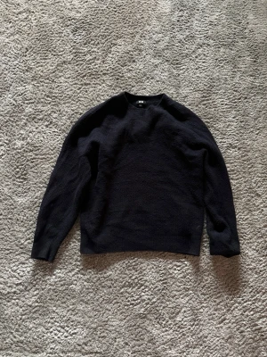 Mörkblå stickad tröja från Uniqlo - En stilren svart stickad tröja från Uniqlo i storlek XS. Tröjan har rund halsringning, långa ärmar och en klassisk rak passform. Perfekt för lager på lager och enkel att matcha med olika outfits.
