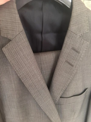 Tiger - Snygg grå diskret mönstrad kostym  - Snygg grå diskret mönstrad kostym i klassisk passform. Kavajen har spetsiga slag, bröstficka och diskreta knapphål på kragen. Perfekt för dig som vill ha en stilren och tidlös look.