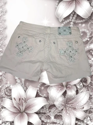 Rosa low waist shorts från Miss Me med bling - Säljer ett par rosa shorts från Miss Me med snygga korsbroderier och glittriga stenar på bakfickorna. Shorts med normal passform, (low waist) klassisk femficksdesign och silverfärgade knappar. Perfekta för sommarens alla äventyr, var igentligen skinny jeans men klipptes till shorts, dem är inte perfekt klippta men de går att fixa! 