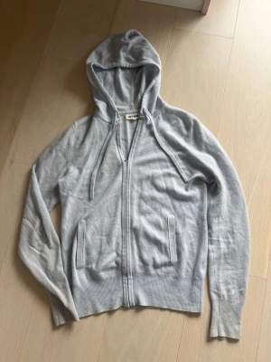Ljusblå zip hoodie soft goat  - Ljusblå zip hoodie från soft goat! Storlek xs, bra skick förutom en liten fläck på framsidan/bröstet (se bild 4) men den syns knappast när man använder den, samt ett litet hål längst ner på armen (se sista bilden), fläcken går troligtvis bort i tvätten och hålet går att laga, annars i jättebra skick!.