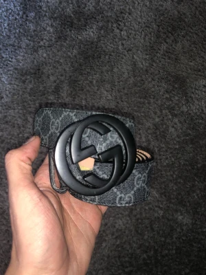 Svart bälte med GG logga - SVART LÄDER BÄLTE MED SVART LOGGA MED 2ST G