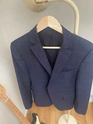 Mörkblå rutig Hugo Boss kavaj - Stilren mörkblå kavaj med diskret rutmönster och klassisk passform. Kavajen har två framfickor med lock och en bröstficka. Perfekt för dig som vill ha en snygg och tidlös look. Strl M men passar också S. Som ny i skicket,enbart använd några gånger! Går för ett par tusenlappar ny! En otrolig kvalitetskavaj!