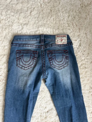 True Religion Jeans  - Säljer mina mörkblå truereligion jeans med röda sömmar, i storlek 25, eftersom dom är för små för mig. Passar Xxs-S skulle jag säga. Midjemåttet är 38cm rakt över och 81cm runt om midjan. Dom är använda men inte slitna, dom är uppsydda och passar dom som är 160-165 typ. Nypris är 1399kr men säljer för 500kr. Pris kan diskuteras💗💗
