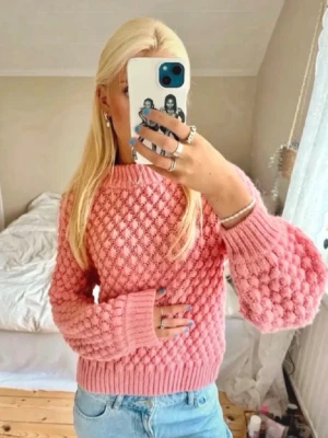 Trendig rosa stickad tröja - Säljer en superfin rosa stickad tröja med bubbligt strukturmönster. Tröjan har ballongärmar och ribbade muddar vid ärmslut och nederkant. Perfekt för dig som vill ha en mysig och trendig look. Materialet känns mjukt och skönt mot huden.💗💗