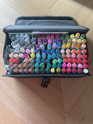 Sanjoki markerset med väska - Stort set med färgglada markers från Sanjoki i en praktisk grå tygväska med spänne. Det följer även med 3 vita highlights pennor jag lagt till själv! Ingen av pennorna är använda, fick hem pennorna för sent och tappade intresse😂🫣