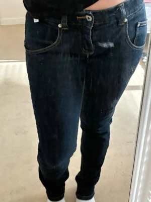 Lie waist Mörkblå raka jeans - Säljer ett par mörkblå jeans med raka ben och kontrastsömmar. Jeansen har klassisk femficksmodell, bälteshällor och knappgylf. Materialet är denim i bomull och passformen är normal. Perfekta till en avslappnad stil.